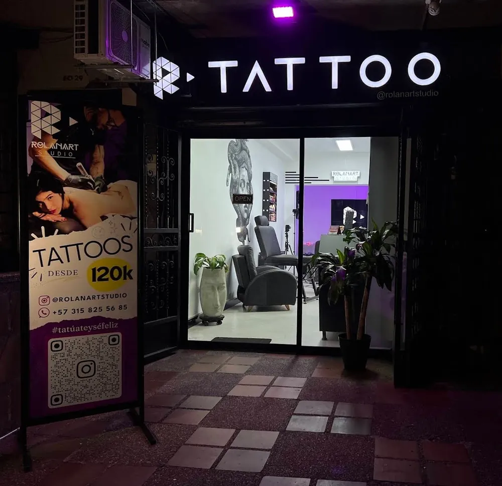 Entrada del estudio con el letrero iluminado Tattoo y el aviso de precios