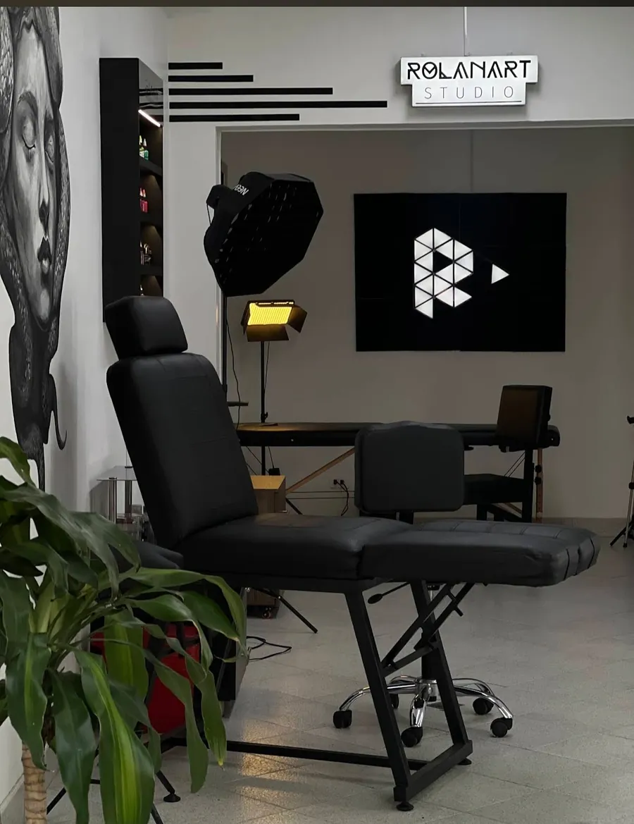 Interior del estudio con camilla negra, luces y el logo en la pared